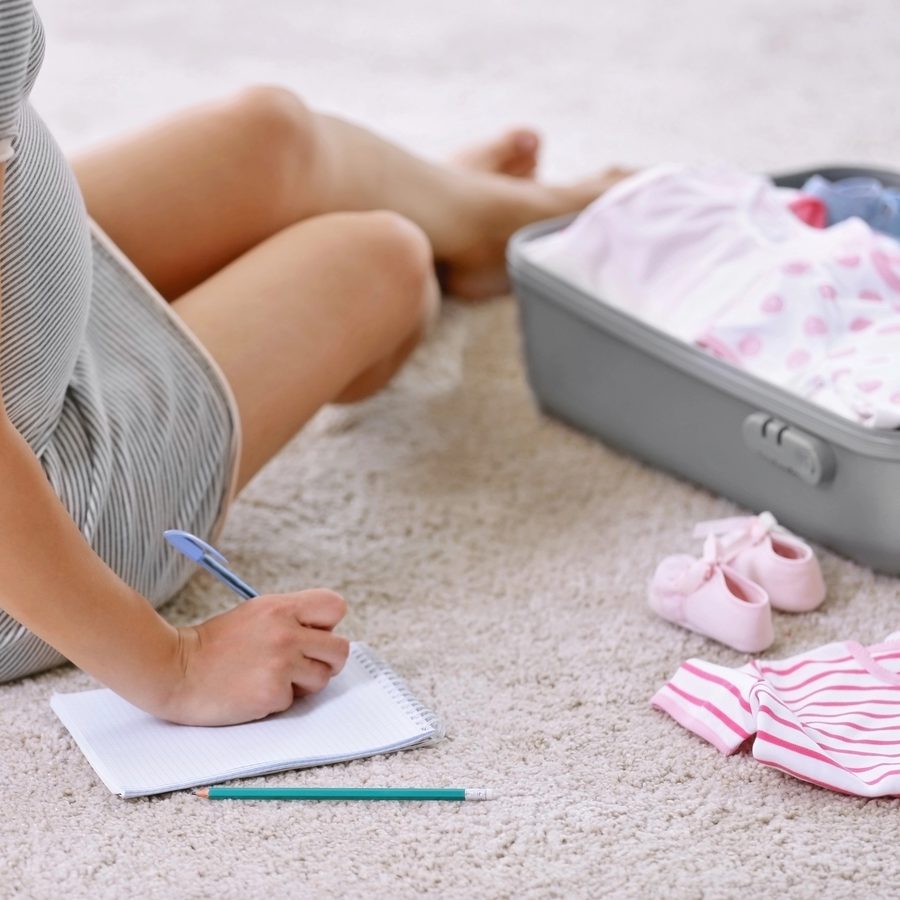 Future maman préparant sa liste de naissance et sa valise de maternité